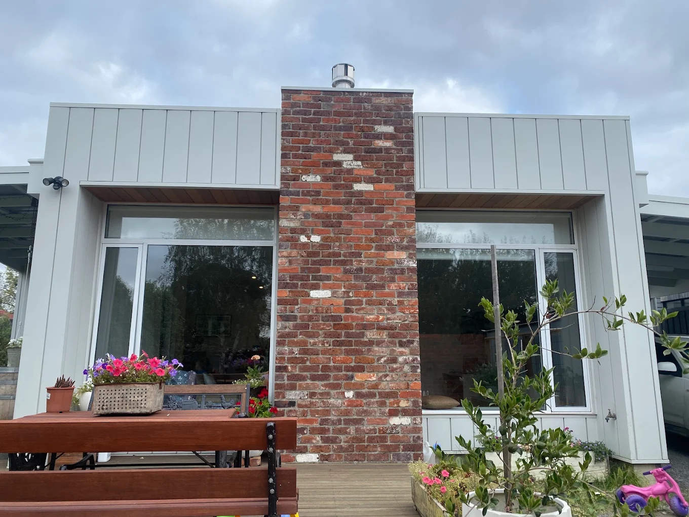 Light grey vertical cladding with exposed brick chimney feature